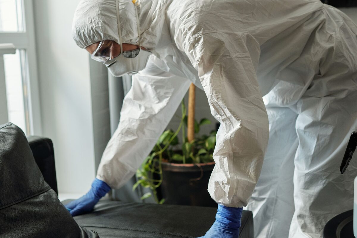 Twee medewerkers in beschermende kleding reinigen een woonkamer
